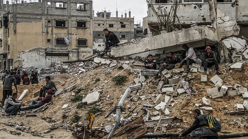 Menschen sitzen auf den Ruinen von Gebäuden, die durch israelische Luftangriffe zerstört wurden. Foto: Mahmoud Issa/dpa