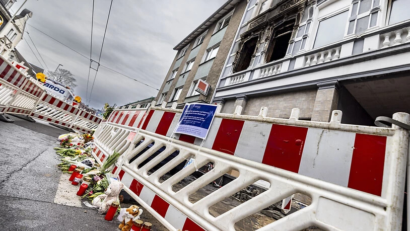 ARCHIV - Blumen und Kerzen liegen vor dem Brandort in Solingen. Nach dem Brand mit vier Toten in Solingen hat die Polizei einen Verdächtigen ermittelt. Der 39-Jährige soll zwei Wochen nach dem Feuer zudem einen Mann mit einer Machete angegriffen und…