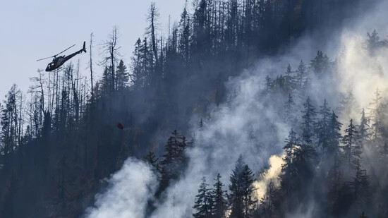 Unter Kontrolle, aber noch nicht gelöscht: Auch nach drei Tagen brennt am Donnerstag, 20. Juli, der Wald oberhalb von Bitsch und Ried-Mörel im Wallis weiter. Ein Helikopter der Air Zermatt bekämpft mit Wasser Brandherde, die nicht am Boden von Feuerwehrleuten angegangen werden können. 