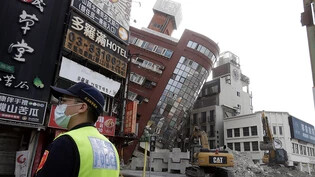 Ein Polizeibeamter steht nach dem Erdbeben in Taiwan neben einem teilweise eingestürzten Gebäude Wache. Foto: ChiangYing-ying/AP