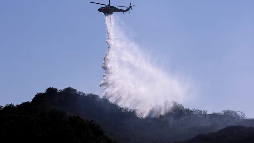 Ein Hubschrauber wirft Wasser ab, um Brandherde in einem Waldbrand in Topanga, westlich von Los Angeles, zu löschen. Die Rauchschwaden der heftigen Waldbrände an der US-Westküste trüben die Aussichten an der knapp 4000 Kilometer entfernten Ostküste. Foto…