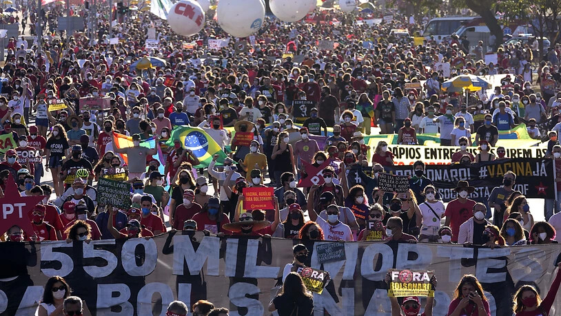Demonstranten halten ein Banner hoch. Tausende Brasilianer sind gegen die Corona-Politik der Regierung von Bolsonaro auf die Straße gegangen. Foto: Eraldo Peres/AP/dpa