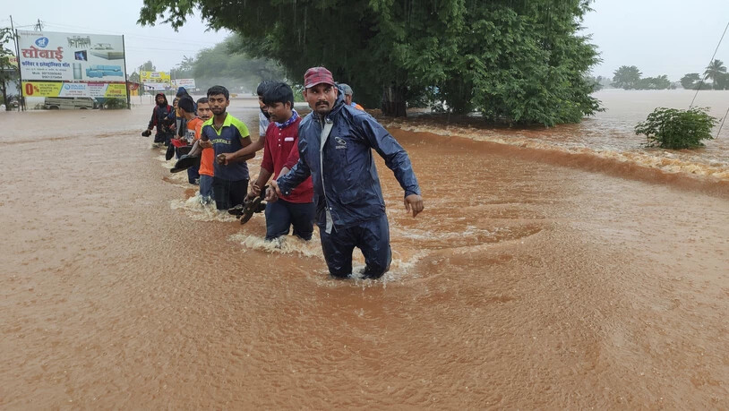 Mitarbeiter der National Disaster Response Force waten durch die Fluten. Der heftige Monsunregen hat mindestens 100 Menschen in Indien das Leben gekostet. Auch die Philippinen sind von den schweren Niederschlägen betroffen. Foto: -/AP/dpa