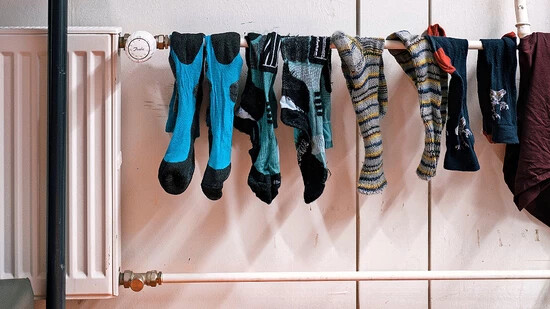 Warm anziehen: Socken brauchen momentan Energie zum Trocknen, später können sie bei etwas kühler justiertem Thermostat die Füsse warm halten.