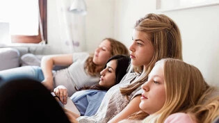 Teenage girls watching TV while relaxing on sofa , model released, property released Copyright: xMaskotx , MA52171