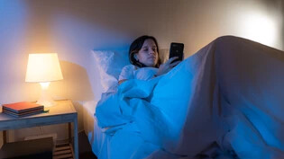 Scrollen im Bett: Inhalte vor dem Einschlafen zu konsumieren, kann negative Gedanken fördern.